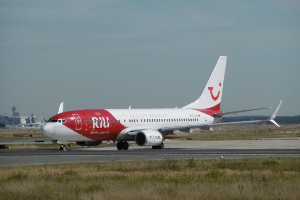 Ferienflieger beim Start - ein Flugzeug von Tui mit Werbung von RIU auf der Landebahn