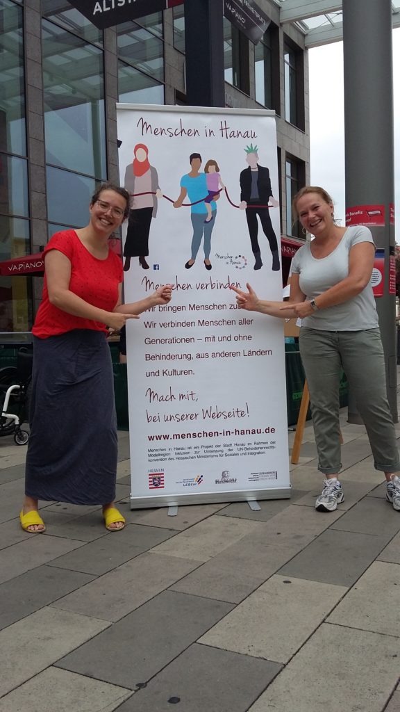 Karin und eine Freundin vor dem Werbeplakat für Menschen in Hanau.