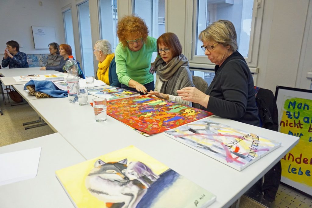 Interessiert werden die Kunstwerke diskutiert. Drei Damen betrachten ein Kunstobjekt.