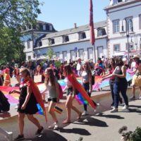 Den Anfang macht ein langes Regenbogen-Banner. Dieses wird an den Seiten von gut zwanzig Menschen gehalten.