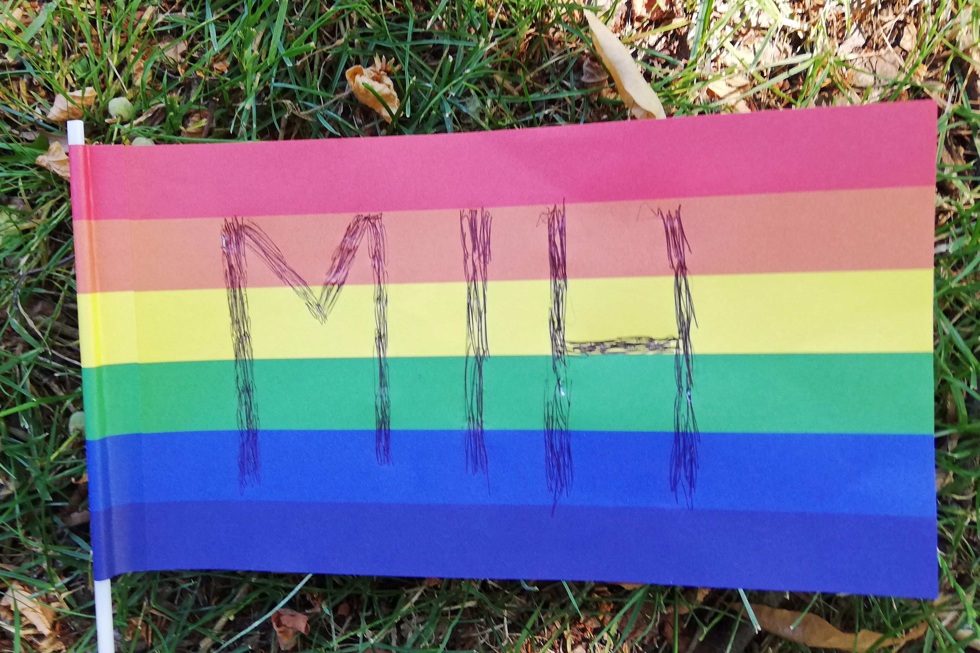 Auf einer großen Regenbogen-Flaage sind die Buchstaben M I H zu erkennen. Diese stehen für den Verein von Menschen in Hanau.