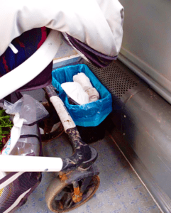 Ein Kinderwagen steht hinter einem Mülleimer auf der Mehrzweckfläche in einem Bus.