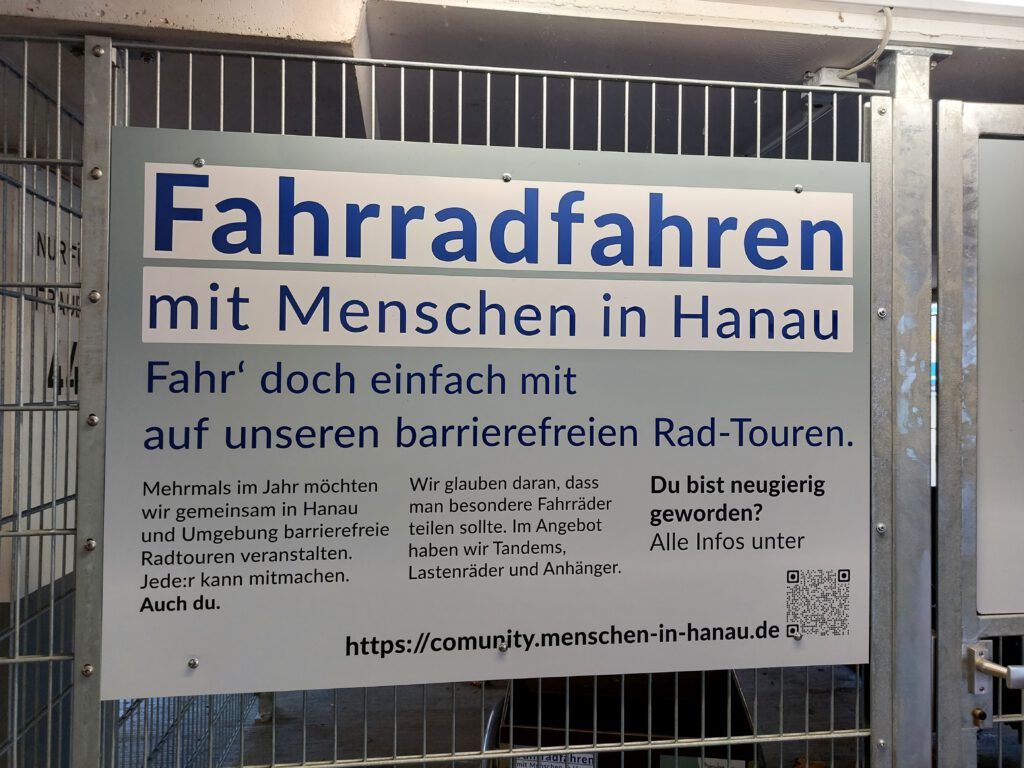 Ein großes Schild an der Radgarage informiert über Fahrradfahren mit Menschen in Hanau