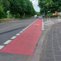 Ein rot markierter Radweg ändert nicht seine Richtung, Der Autoverkehr muss beim Abbiegen den Radweg kreuzen.