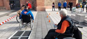 Ein Jugendlicher im Rollstuhl fährt zwischen Hindernissen Parcours.