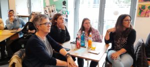 2024: Pub-Quiz. Mehrere Frauen schauen nachdenklich und aufmerksam in Blickrichtung einer nicht sichtbaren Bühne. Auf den Tischen stehen Getränke.