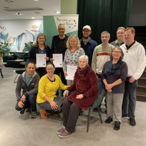 2024: Das Checker-Team mit mehreren Geschäftsinhabern feiern den Auftakt von Check & Map. Das Foto entstand im Service-Laden-Hanau. Einige Geschäftsinhaber halten ein Zertifikat in den Händen.