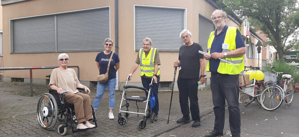 Die Gruppe steht vor einem Haus mit heruntergelassenen Rollläden.