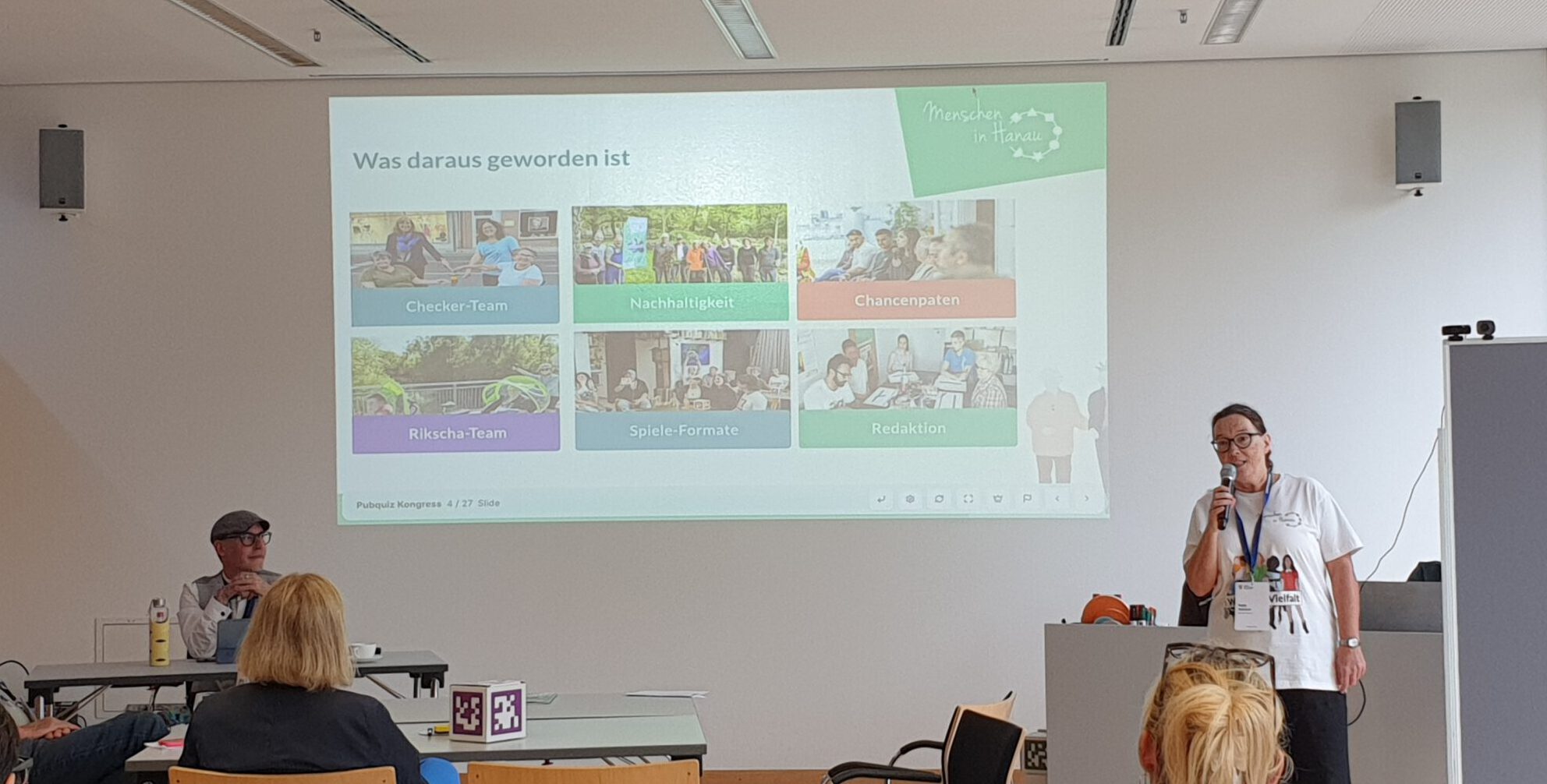 Foto vom Kongress „Dein Ehrenamt 2026“: Menschen sitzen in einem Veranstaltungsraum und nehmen an einem Quiz teil. Katja stellt den Verein vor