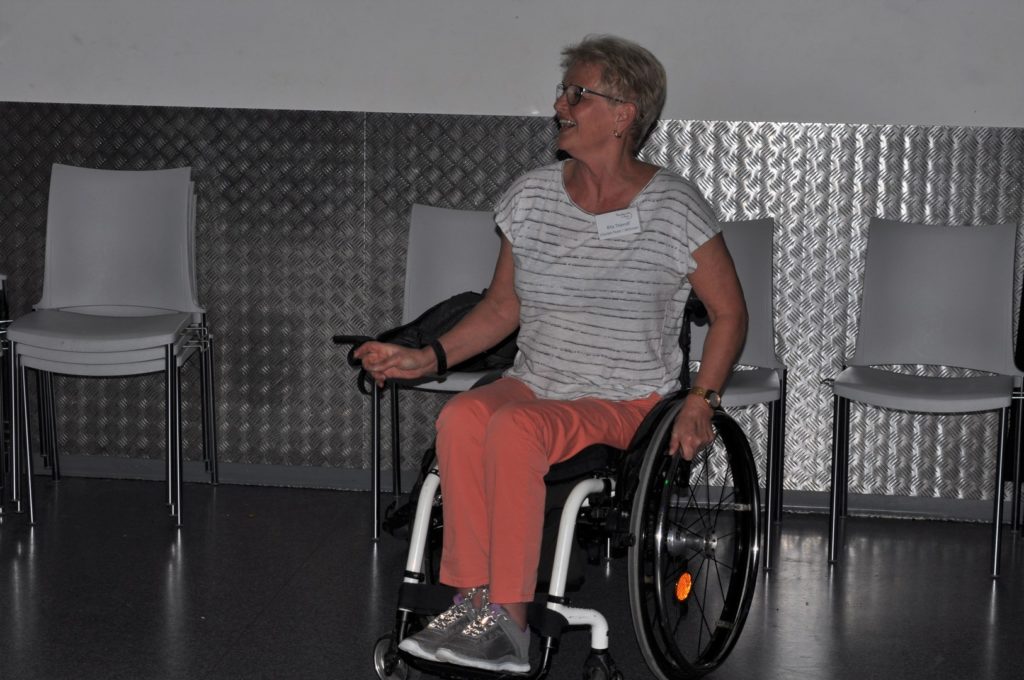 Das Bild zeigt Rita, die in ihrem Rollstuhl rhytmisch zu den Klängen tanzt.