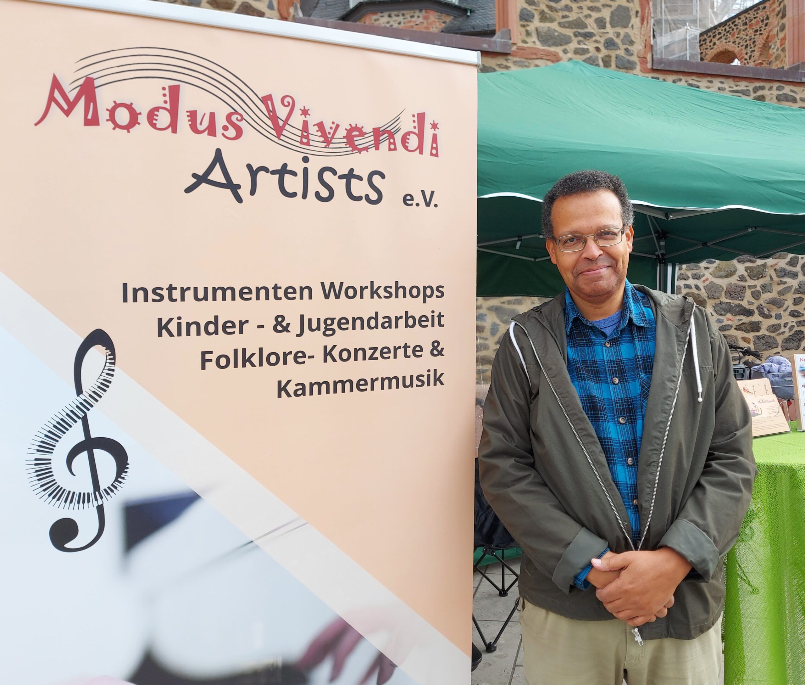 Ein Herr steht neben dem Banner von Modus Vivendi Artist