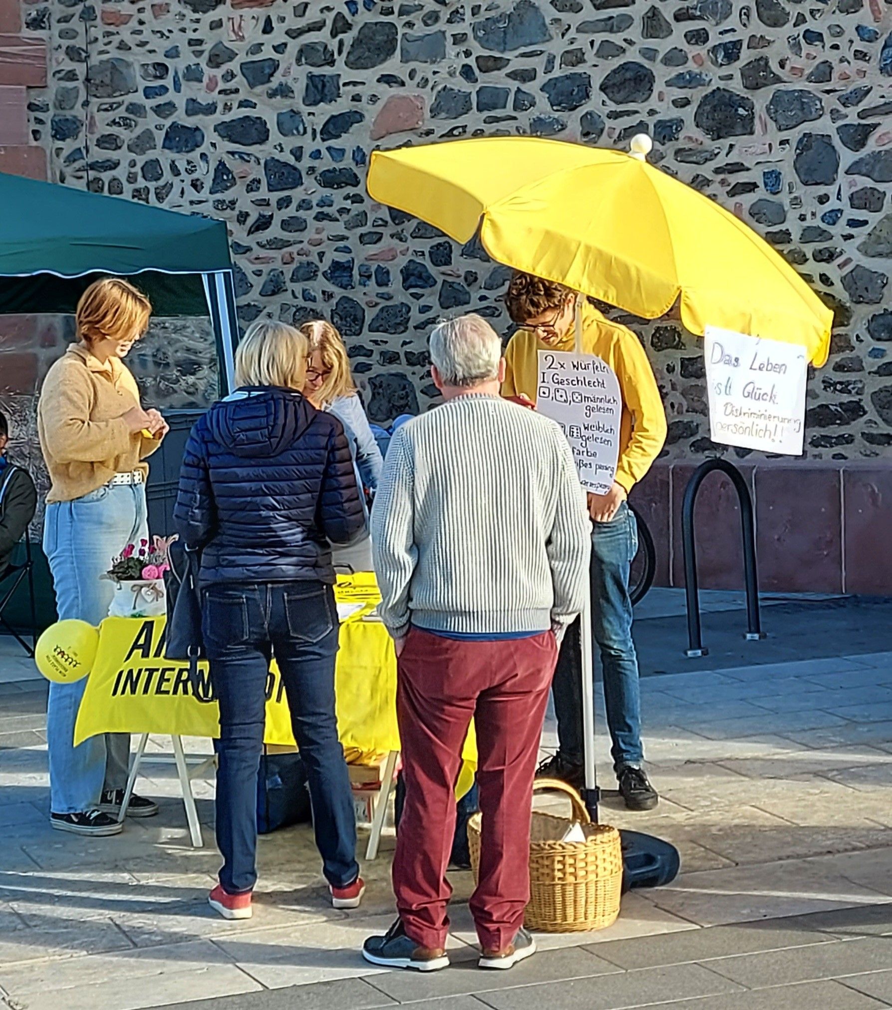 Personen erkundigen sich am gelben Stand von Amnesty International