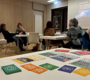 Spielkarten auf einem Tisch mit Personen im Hintergrund