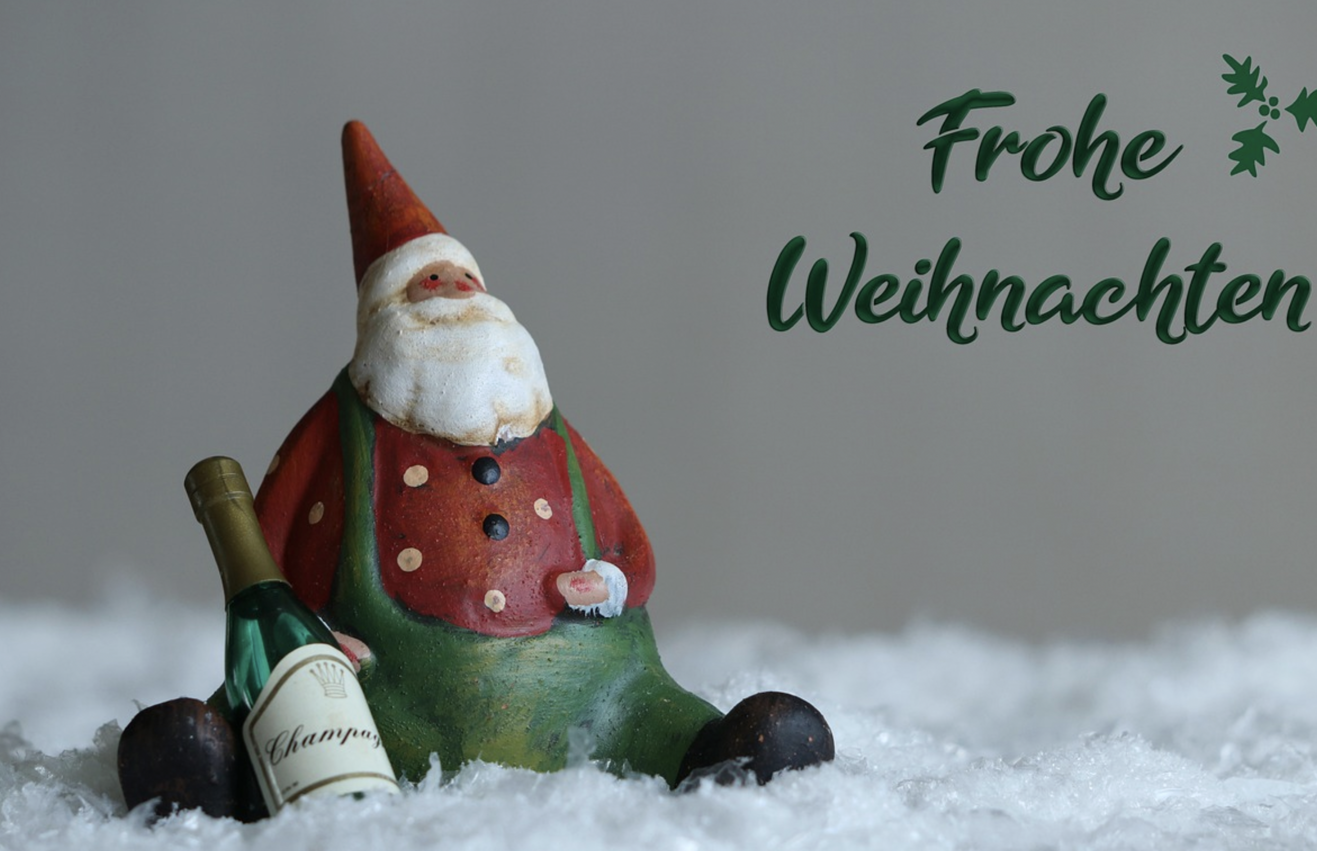 Eine Weihnachtsmann Gartenfigur mit einer kleinen Champagner-Flasche und der Aufschrifft "Frohe Weihnachten"