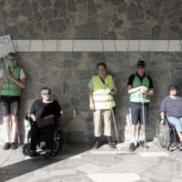 7 Menschen in einer Reihe vor einer Steinwand mit Warnwesten. Es ist das Checker-Team von Menschen in Hanau