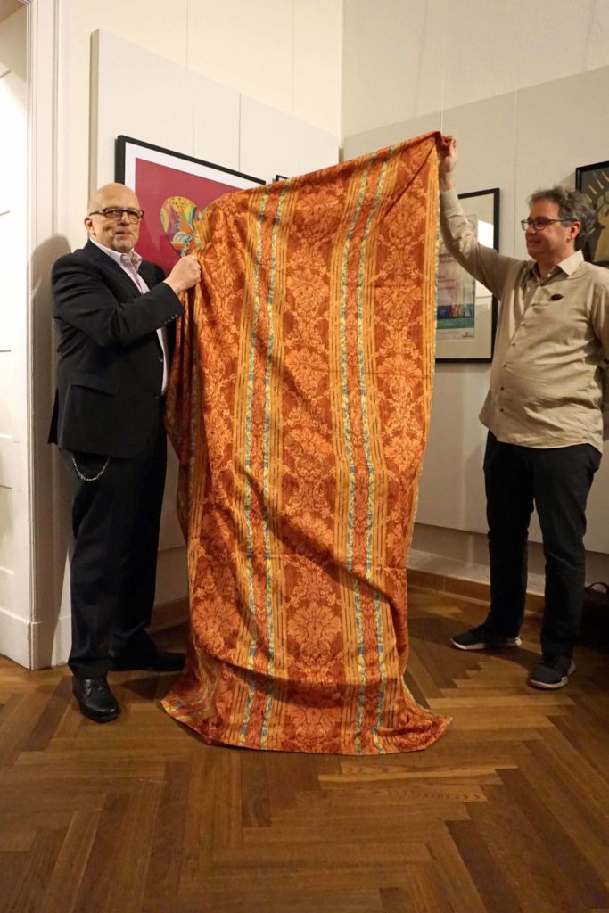 Bürgermeister W. Axel Weiss-Thiele und Peter Koch, Zeichenakademie enthüllen das erste zu versteigernde Bild. Es ist mit einer roten Decke abgedeckt.