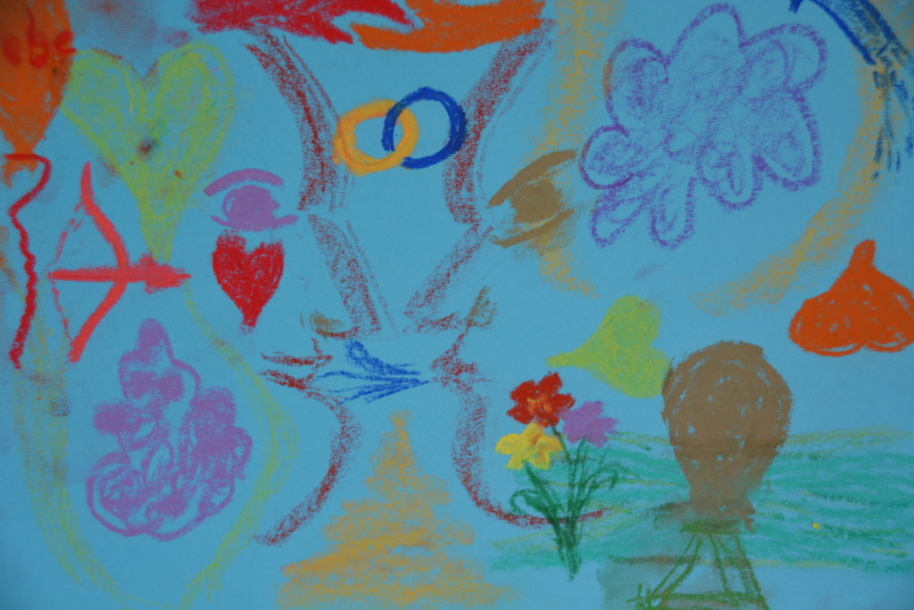 Abstrakt gemalt mit zwei Gesichtern von der Seite, die sich für einen Kuss annähern. Drum herum sind viele Zeichen der Liebe (Herzen, Eheringe) dargestellte und bunte Farben genutzt.