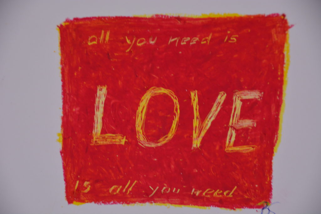 Auf rotem Hintergrund ist in Gelb hervorgehoben das Word Love. Unten und oben steht dann jeweils 'all you need is'.