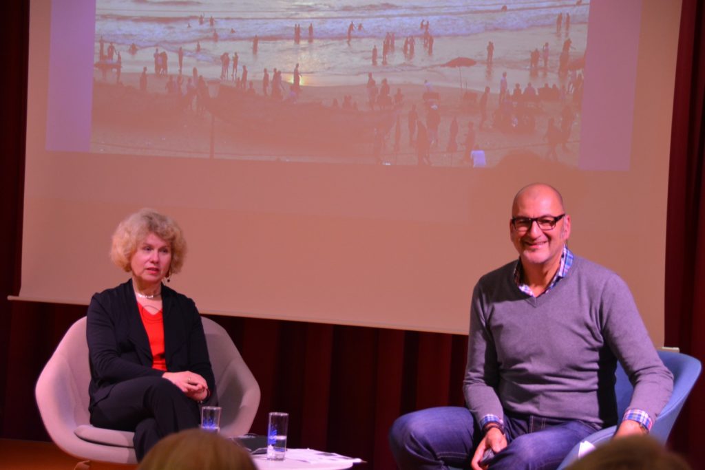 Das Bild zeigt Silvia Schäfer und den Moderator auf der Bühne sitzend und dahinter ein Bild einer der Reisen.
