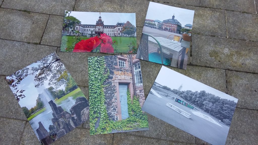 Fünf der insgesamt zwölf ausgewählten Fotos zum Projekt 'Lieblingsorte' liegen auf einem Steinuntergrund.