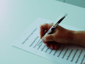 Eine Hand hält einen Stift und unterstreicht Wörter in einem Text.