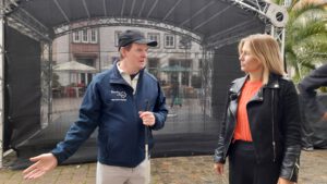 Boris spricht mit Kate Menzyk. Boris trägt eine blaue Jacke mit der Aufschrift Menschen in Hanau und eine blaue Kappe. Kate Menzyk trägt eine schwarze Jacke und ein orangefarbenes Shirt.