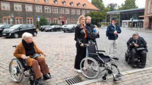 Gaby und Bärbel im Rollstuhl, stehend Boris, Kate Menzyk und ein HR-Mitarbeiter mit Mikrofon. Alle lachen.