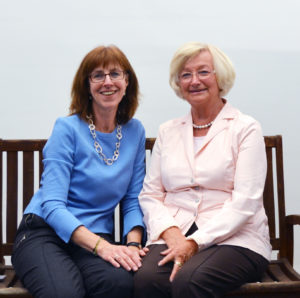 Fahrten-Leiterinnen Sylvie Janka (sitzt links) und Rita Hoffmann (sitzt rechts) auf einer Holzbank.