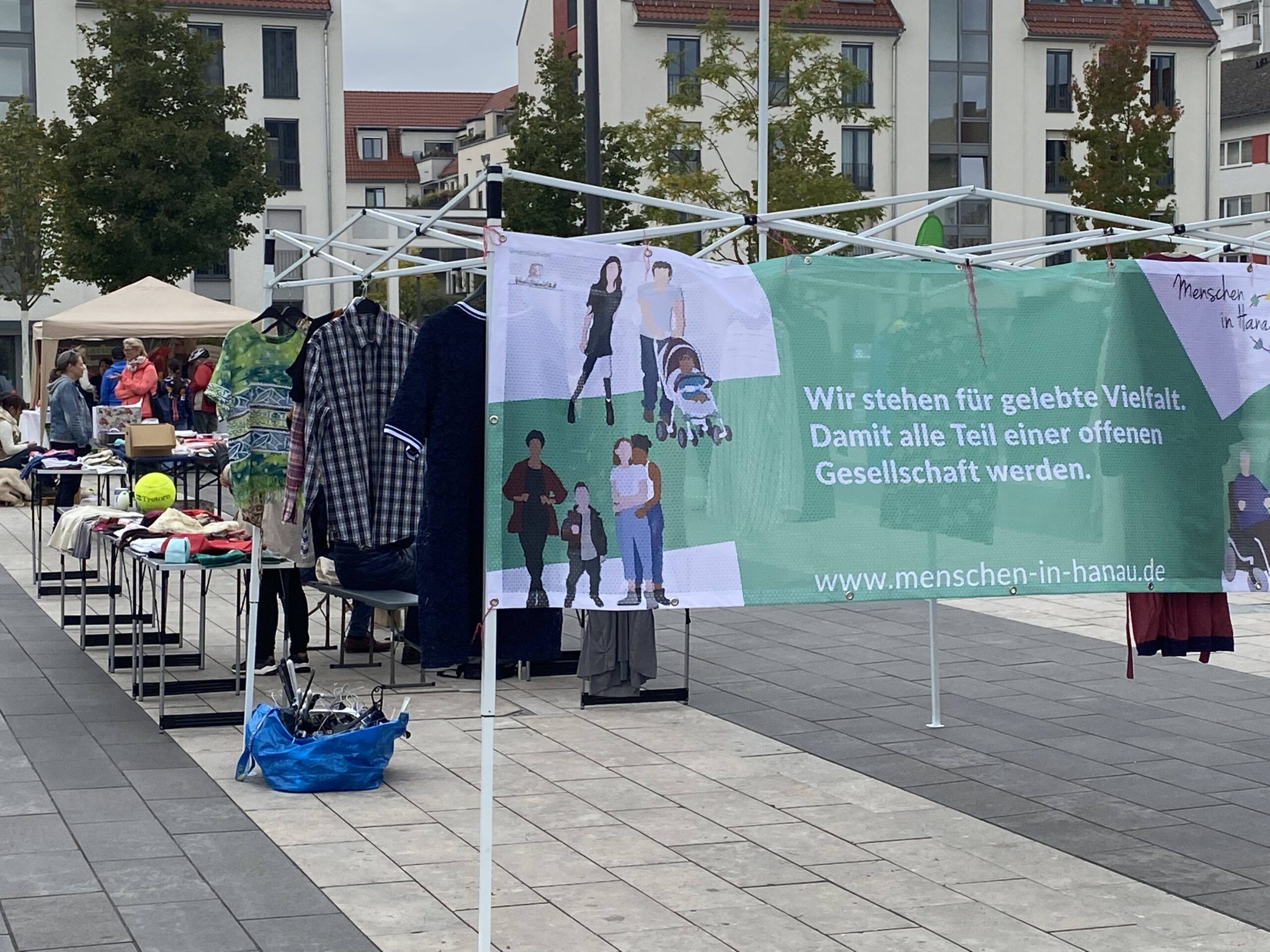 Grüner Menschen in Hanau Banner mit den dahinterliegende Tauschständen