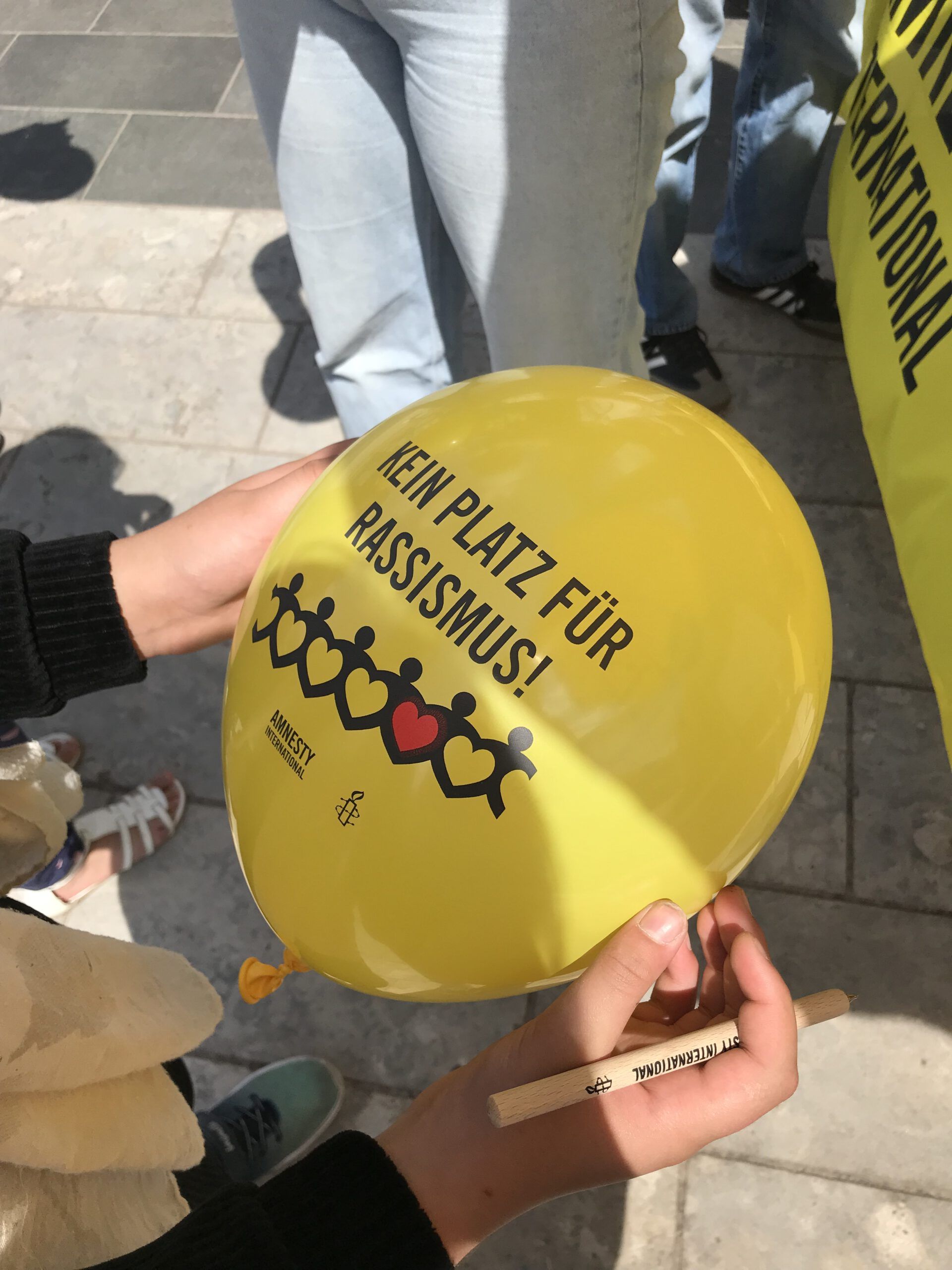 Ein gelber Luftballon auf dem "Kein Platz für Rassismus" geschrieben steht.