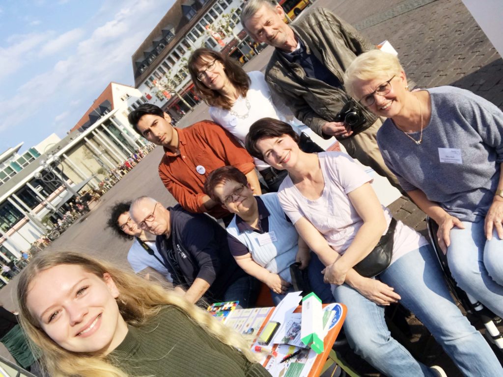 Gruppenaufnahme. Die Gruppe sitzt schräg, da es ein Selfie vom Team Menschen in Hanau ist