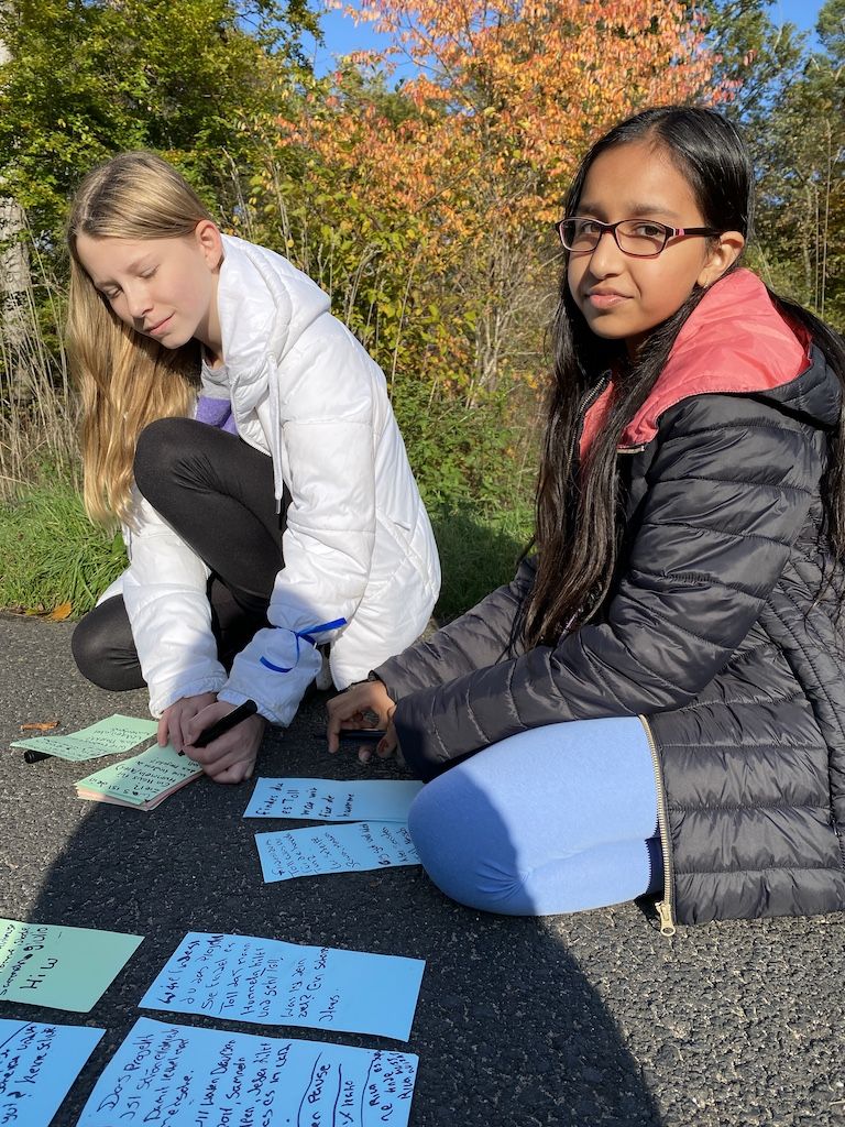 2 Schülerinnen der 6c sitzen auf dem Boden und sortieren ihre Notizen