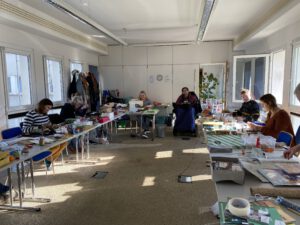 2022: Mehrere Personen, darunter auch ein Mann im Rollstuhl, gestalten kreative Dinge für die Winter-/Weihnachtszeit.