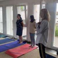 3 Frauen stehen nebeneinander auf unterschiedlich farbenen Yoga-Matten