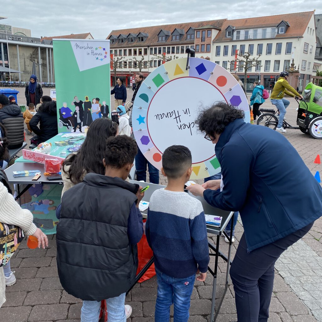 Eine engagierte Dame vom Verein "Menschen in Hanau" erklärte drei Kindern anschaulich, wie wichtig das Glücksrad mit Fragen rund um das Thema Inklusion und Barrierefreiheit ist.