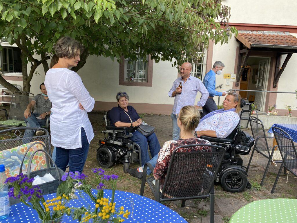 Beim Sommerfest kommen Menschen im Rollstuhl, Menschen mit Sehbehinderung und Mensche ohne erkennbare Behinderung zusammen und tauschen sich aus.