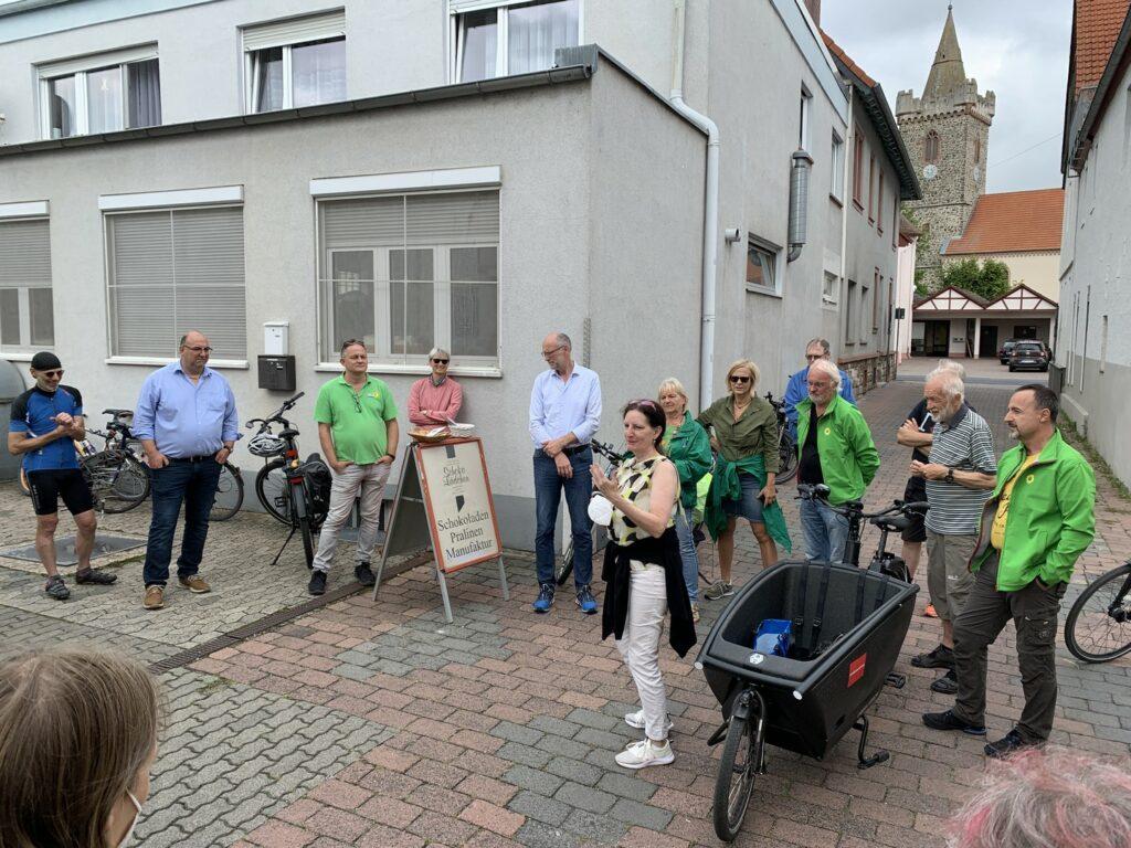 Rede der Inhaberin vom Schokolädchen. Die Teilnehmenden stehen um sie herum, das Lastenfahrrad der Stadt Hanau steht gut sichtbar direkt in der Mitte.
