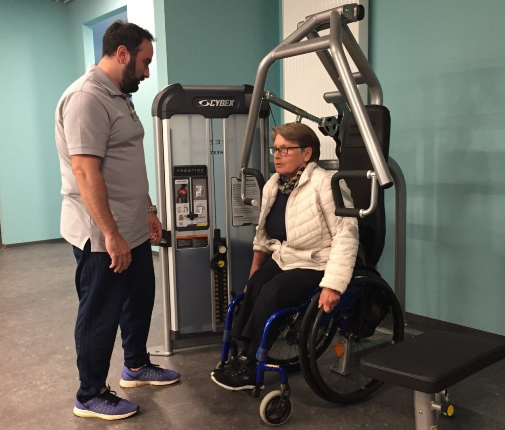 Marianne probiert sich mit den ersten Übungen. Die Geräte sind so konstruiert, dass man in seinem Rollstuhl selbst drunter bzw. ran fahren kann.