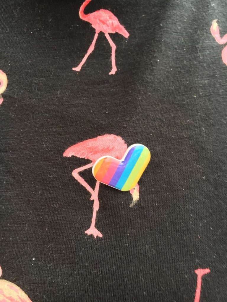 Condor hat kleine Herzen in Regenbogen-Farben verschenkt. Hier steckt eines auf einem Tshirt mit rosaroten Flamingos.