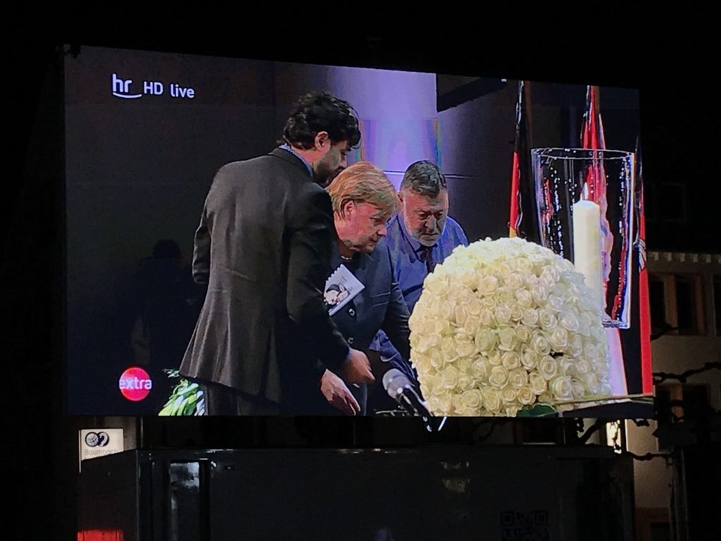 Weiße Blumen werden auf einem Tisch abgelegt, Im Bild Angela Merkel mit Angehörigen.