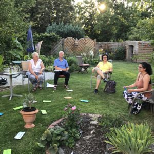 2020: Diskussions-Raum. Mehrere Personen sitzen in einem Garten, auf dem Rasen liegen Moderationskarten. Dies war kurz vor der Vereinsgründung.