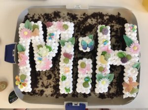 2020: Ein Kuchen in Buchstabenform von MiH mit dickem Zuckerguss und Blüten aus Zucker zur Gründungssitzung