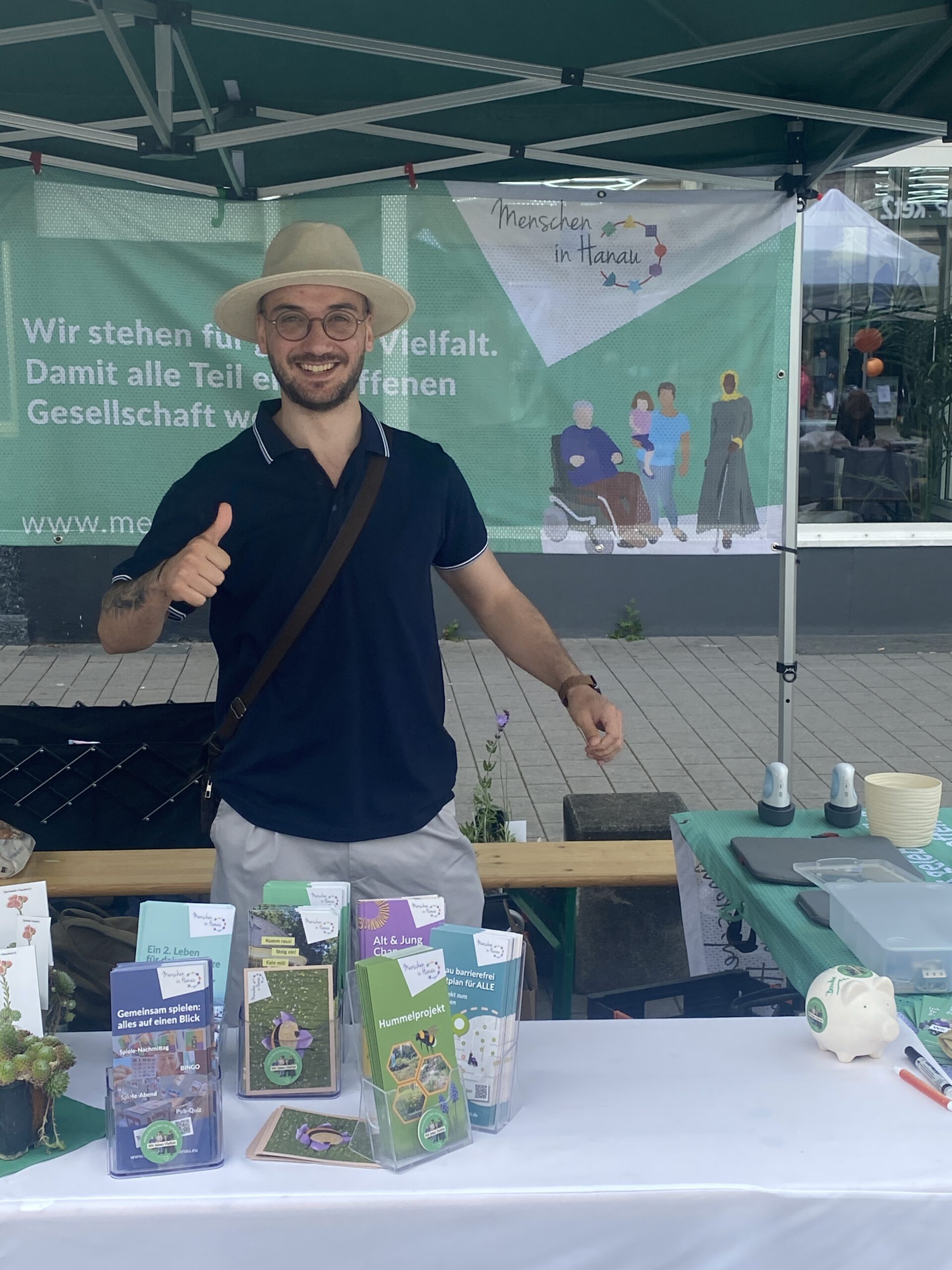 Majd steht am MIH-Stand und zeigt den Daumen hoch.