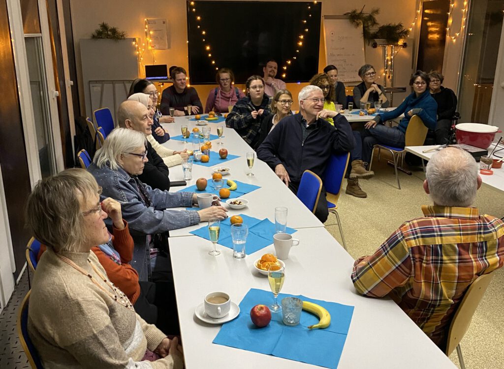 Viele Menschen sitzen um einen Tisch der geschnmückt ist