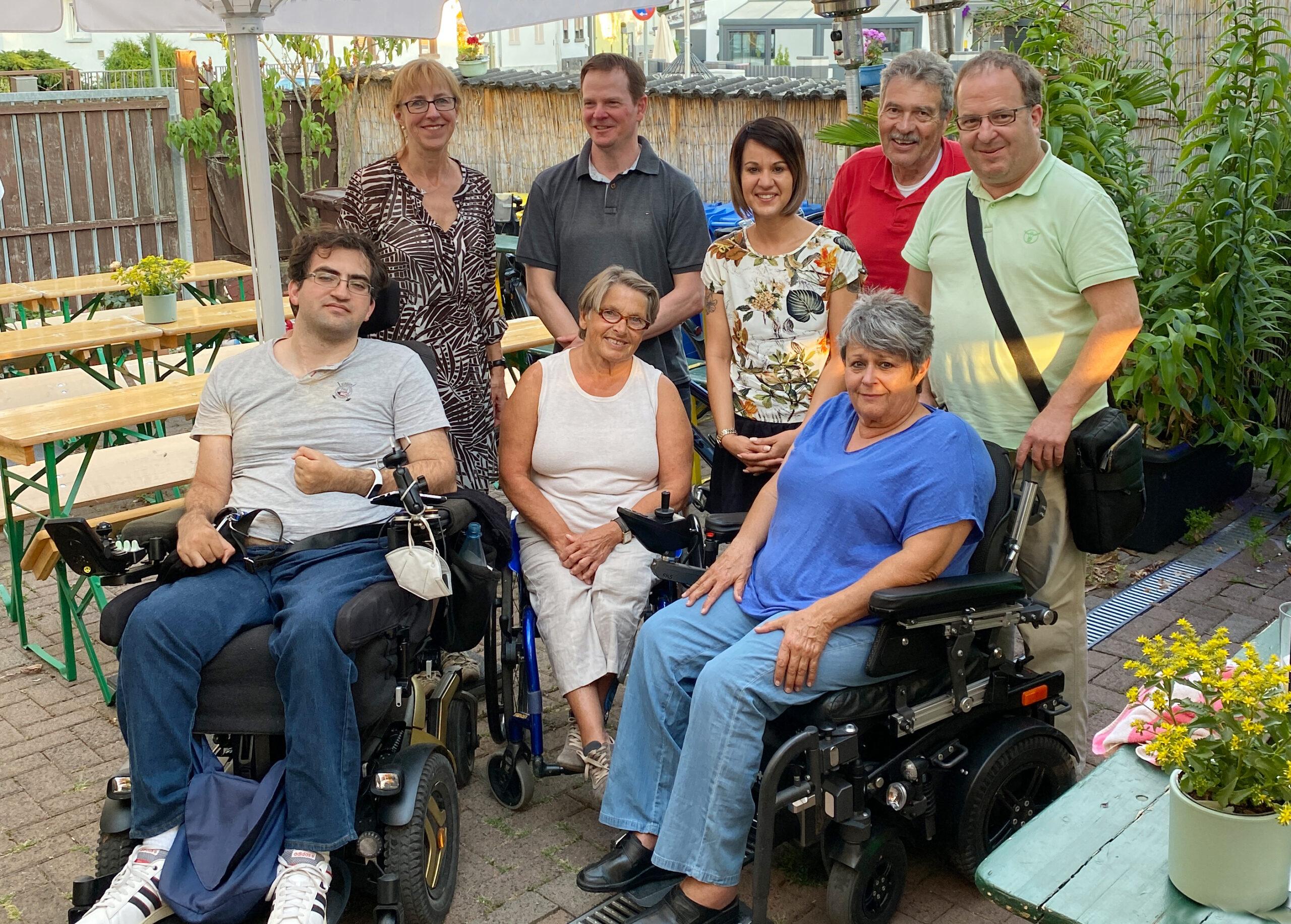 Eine Gruppe Menschen mit und ohne Rollstuhl steht für ein Gruppenfoto zusammen.