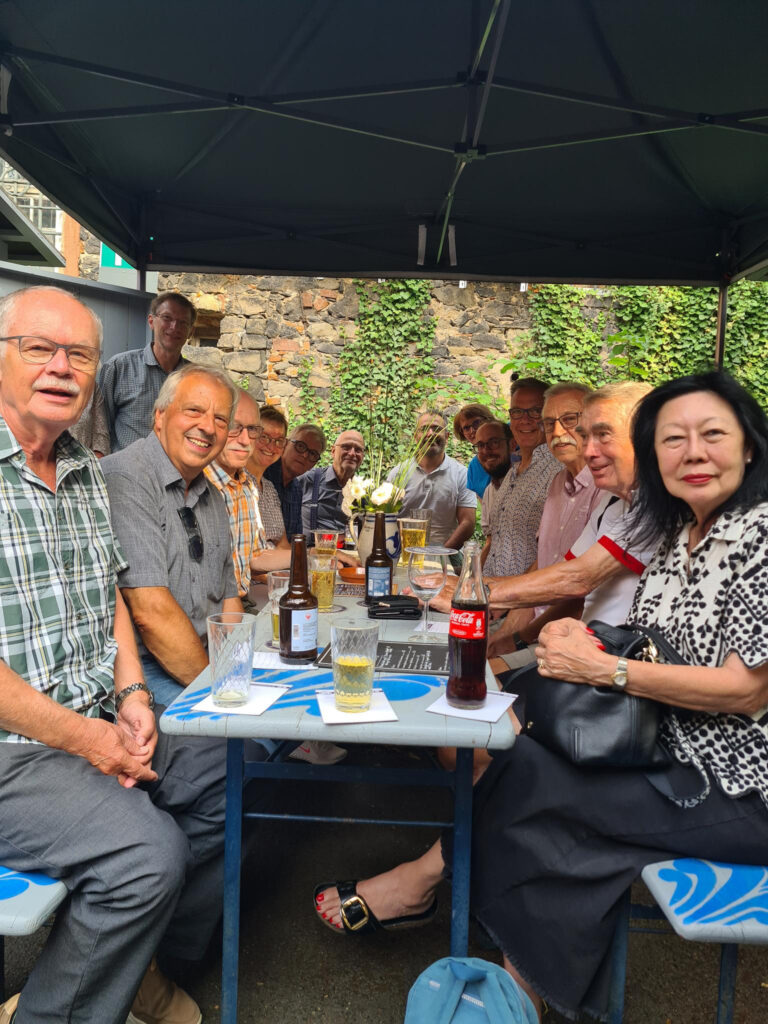 MEnschen sitzten um eine blaue Bierzeltgarnitur