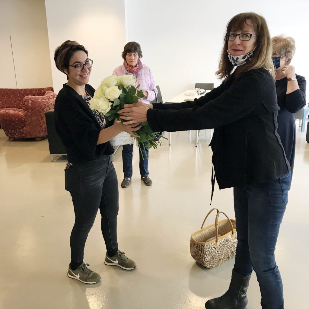 Sylvie (rechts im Bild) übergibt einen Strauß weißer Rosen an eine junge Frau der Initiative (linke Seite im Bild).