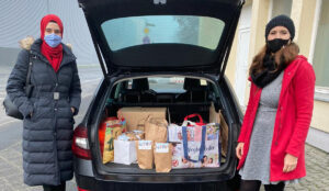 2020: Geschenke für das Franziskus-Haus. 2 Frauen stehen neben einem Auto. Der Kofferraum ist geöffnet und darin sind Geschenktüten.