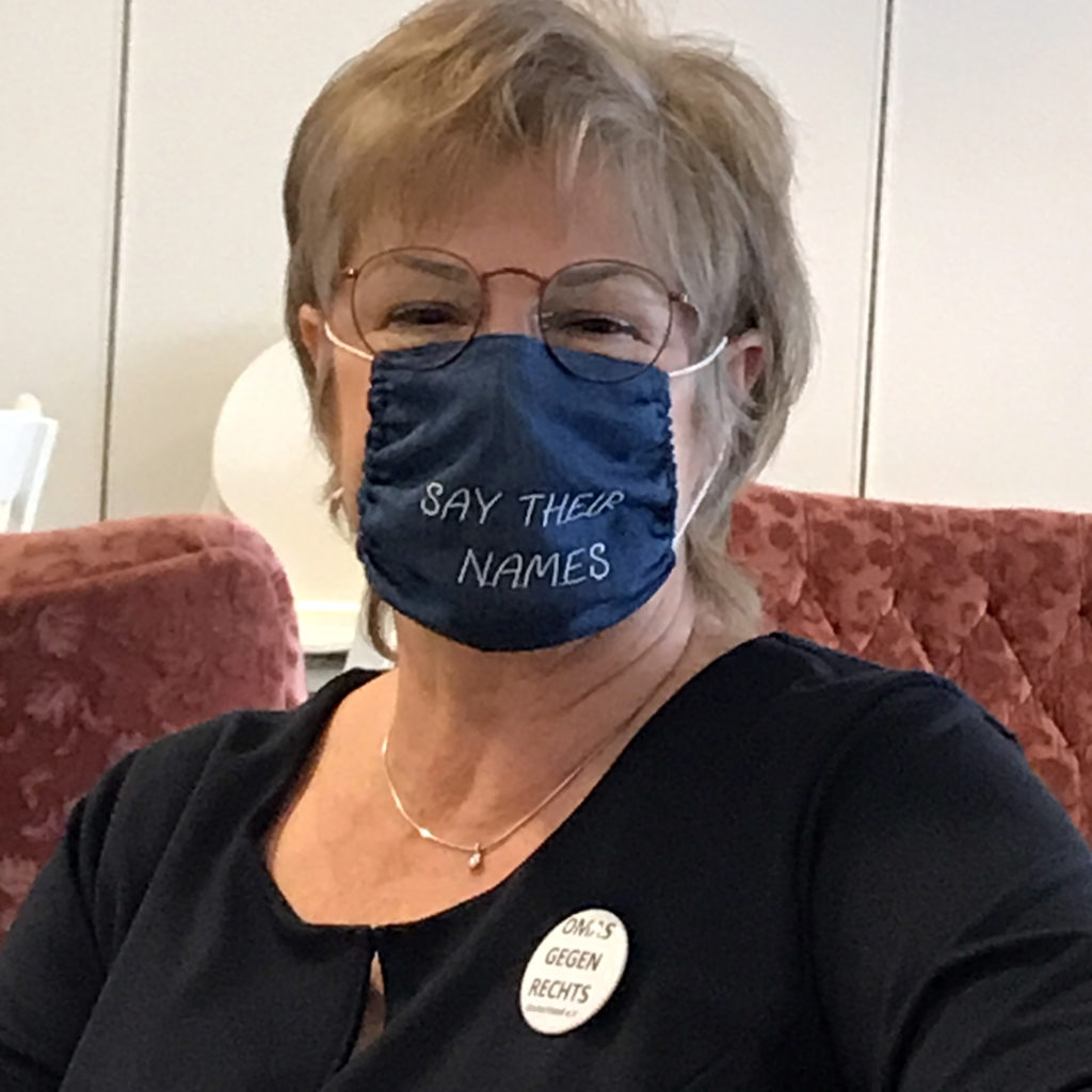 Gesicht einer Frau - Heike Arnold - mit einer Maske aus Jeansstoff mit der Stickerei "Say there names"