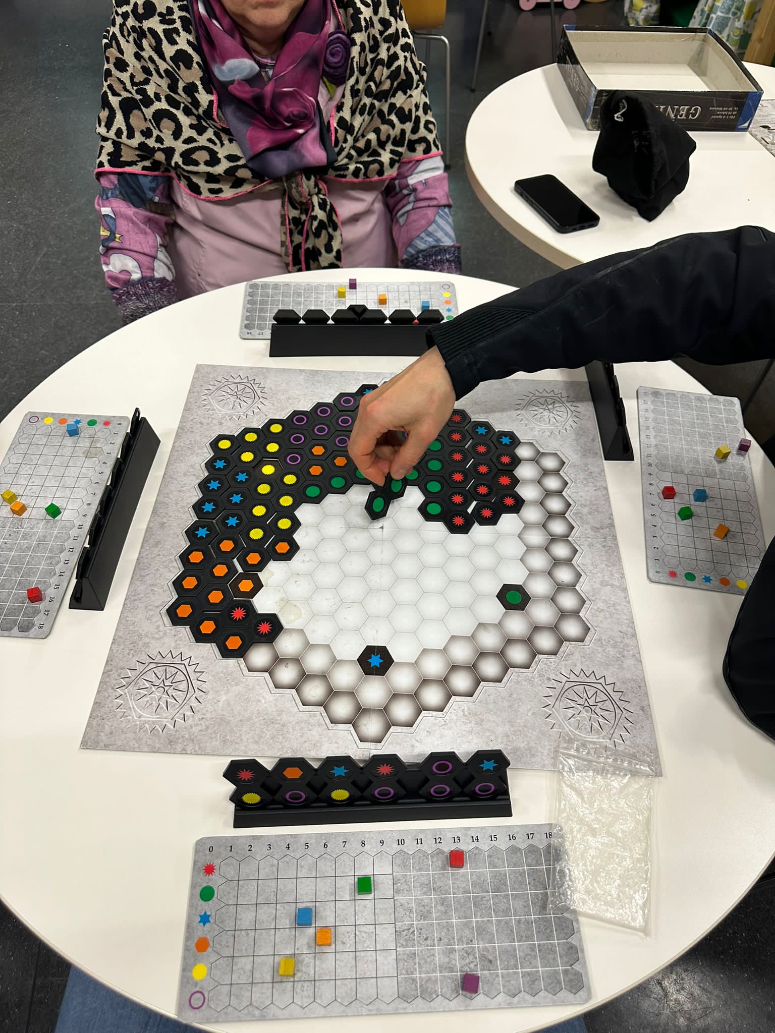 Das Bild zeigt den Tisch mit dem Spielbrett des Spiels "Einfach Genial". Farben sollen hier aneinander gelegt werden.